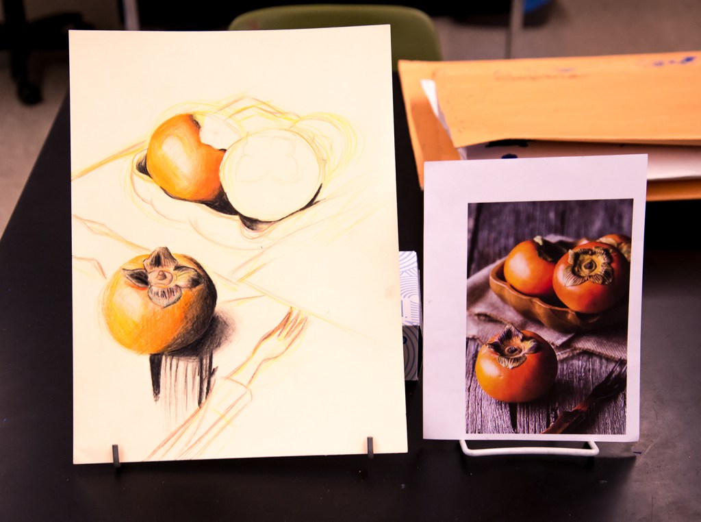 7th grade colored pencil still life in progress of persimmons in a bowl on a table