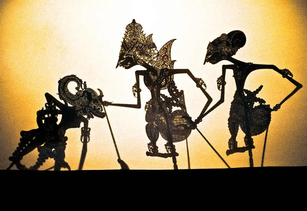 Wayang Kulit shadow puppets against a luminous backlit screen