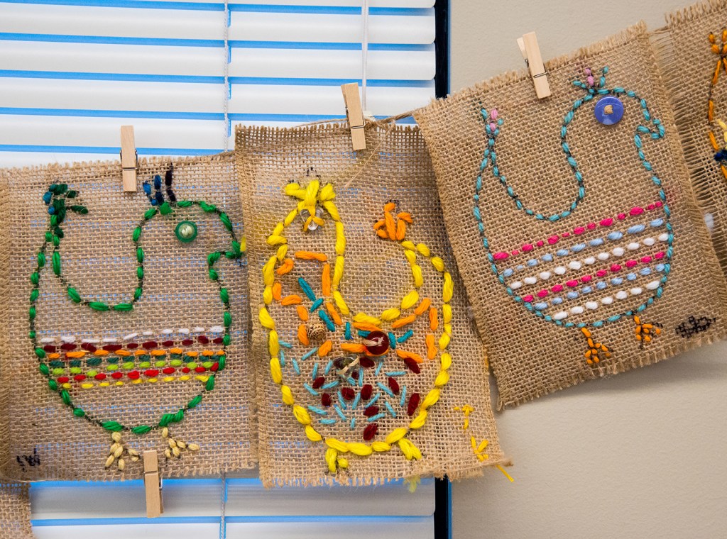 Three examples of 3rd grade students' sewing samplers depicting colorful, whimsical chickens