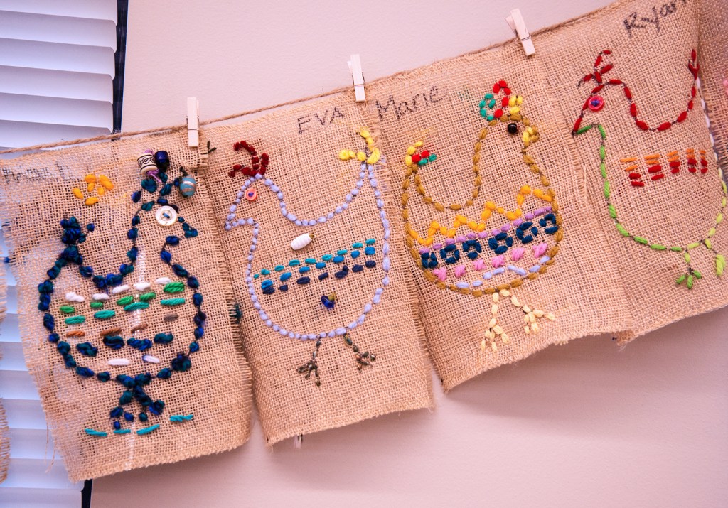 Four examples of 3rd grade students' sewing samplers depicting colorful, whimsical chickens