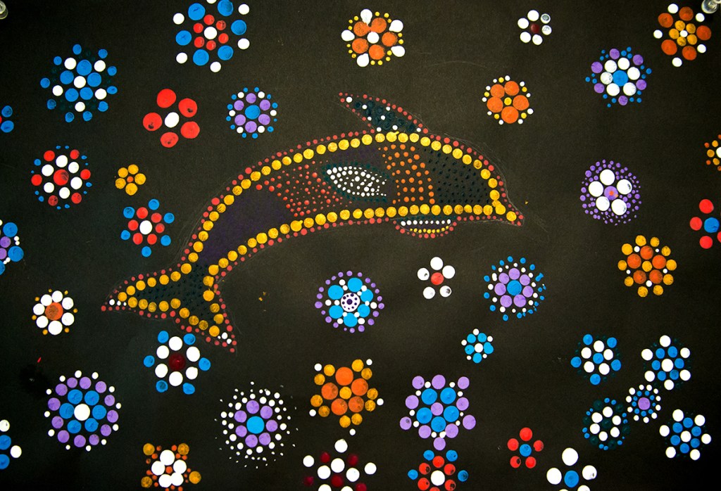 5th grade student's Aboriginal-style Dot Painting of a dolphin among colorful floral patterns.