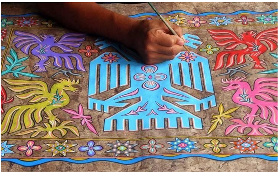 A Mexican artisan working on an Amate painting, depicting traditional subjects, such as birds and flowers, in vibrant colors on Amate bark paper.