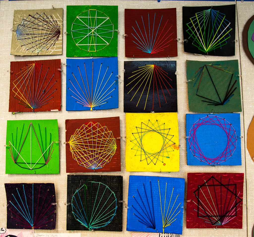 Sixteen different examples of the cardboard-square format, woven geometric string designs by 4th grade students in a variety of patterns and colors.