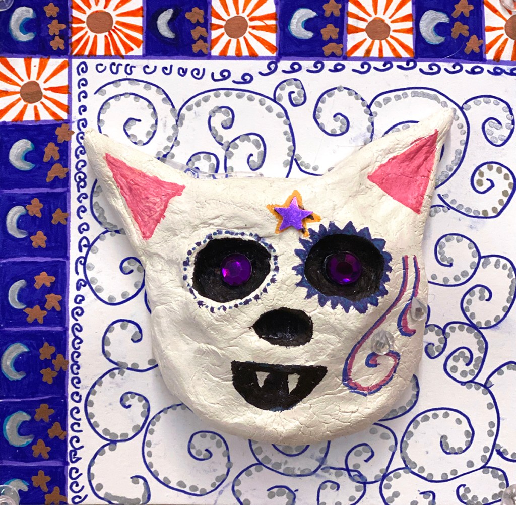 An example of a 4th grade student's clay skull, designed to imitate a Día de los Muertos (Day of the Dead) sugar skull, with a colorful, festive patterned background