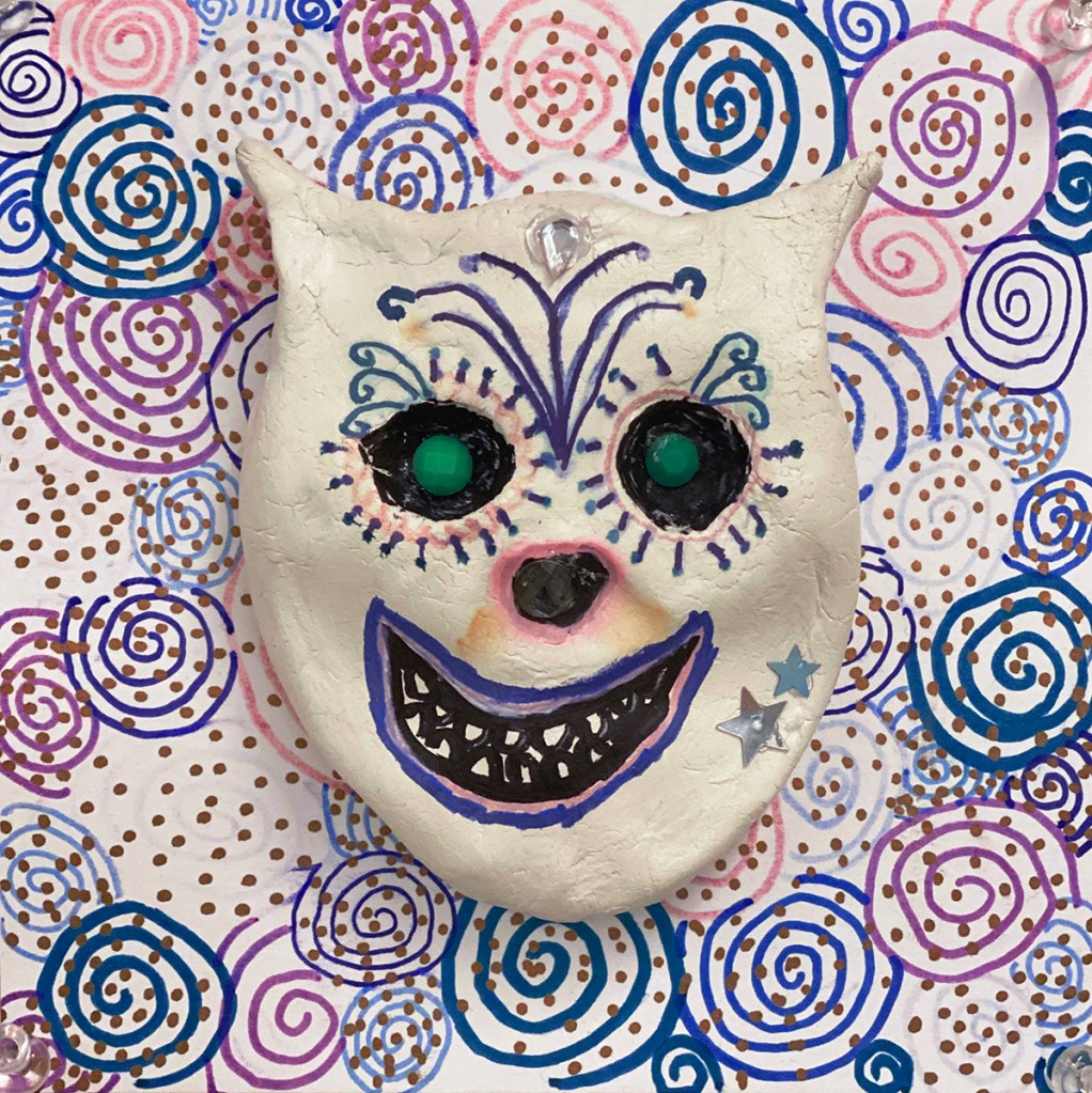 An example of a 4th grade student's clay skull, designed to imitate a Día de los Muertos (Day of the Dead) sugar skull, with a colorful, festive patterned background