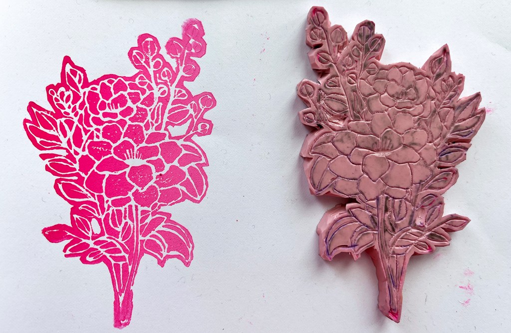An 8th grade student's linoleum block print and carved linoleum block. The print is a bouquet of flowers in pink ombre.