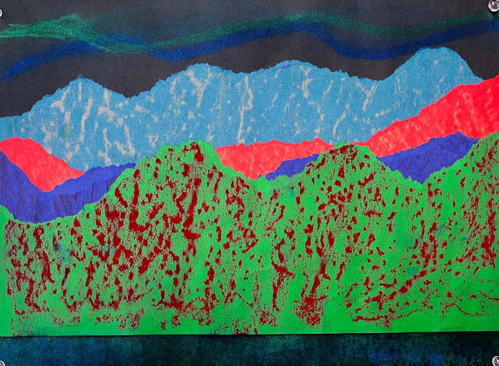 An example of a northern lights landscape by a second grade student. This example has deliberately torn paper in red, green, turquoise and blue, with texture plates used to rub different textures in oil pastel to give the illusion of textured hills and mountains. The lights above are swirled in blue and green, with those same colors more softly expressed in the reflection of the lake below.