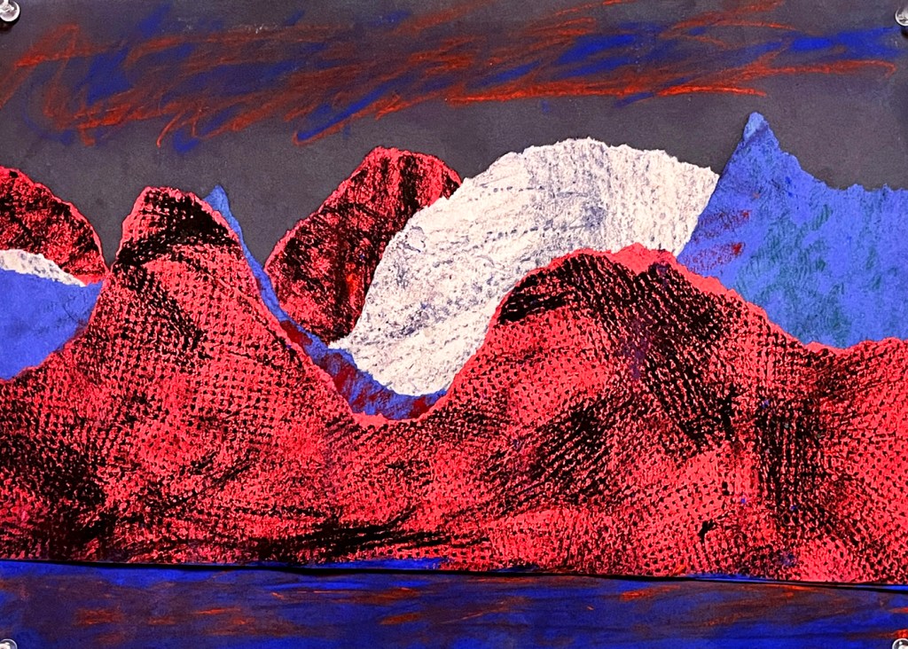 An example of a northern lights landscape by a second grade student. This example has deliberately torn paper in red, gray and blue, with texture plates used to rub different textures in oil pastel to give the illusion of textured hills and mountains. The lights above are swirled in blue and red, with those same colors more softly expressed in the reflection of the lake below.