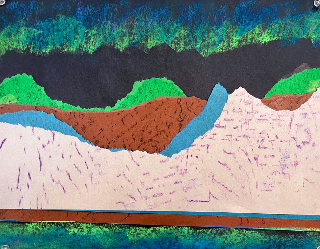 An example of a northern lights landscape by a second grade student. This example has deliberately torn paper in turquoise, green, gray and brown colors, with texture plates used to rub different textures in oil pastel to give the illusion of textured hills and mountains. The lights above are swirled in blue and green, with those same colors more softly expressed in the reflection of the lake below.
