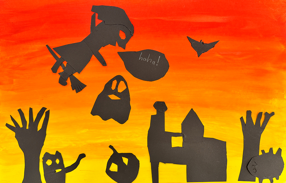 1st grade spooky Halloween scene. Black silhouettes on a painted sunset sky (red, orange, yellow). The silhouettes are of a ghost, a cat, a bat, a haunted house, bare trees, a witch flying on her broom saying "ha ha" and a jack-o'-lantern.